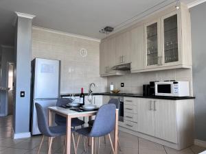 Una cocina con mesa y sillas y un refrigerador. en EasyCapeTown - Entire Flat in Big Bay, en Cape Town