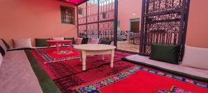 a room with a table and a red rug at Chambre partagée Hostel DAIFLAH in Oulad Rguia