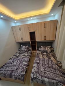 two beds in a room with wooden cabinets at PORTO MATRUH-modern home in Marsa Matruh