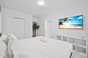 a white bedroom with a bed and a tv on the wall at Harding Apartments by Andes STR in Miami Beach +174 photos