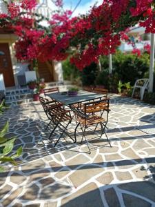 a table and chairs on a stone patio with pink flowers at Villa Joanna-1 in Batsi