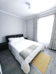 a bedroom with a white bed and a window at The Residence Apartments in Maseru