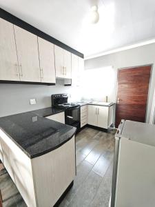 a kitchen with white cabinets and a black appliances at The Residence Apartments in Maseru