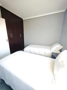 two beds in a hotel room with white sheets at The Residence Apartments in Maseru