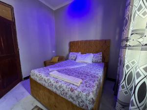 a bedroom with a bed with a purple comforter at Viva Lodge in Kilindoni