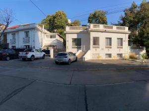 a white house with two cars parked in a parking lot at Eco Dpto Estudio El golf 9 in Santiago