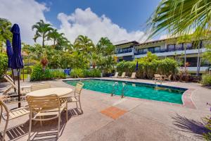 a pool with tables and chairs next to a building at 50 Feet to Ocean Kona Deluxe Ground-Floor Unit! in Kailua-Kona
