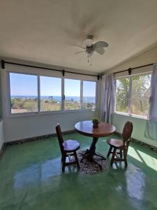 ein Esszimmer mit Tisch und Stühlen und Fenstern in der Unterkunft Casa de las Aves in Puerto Escondido