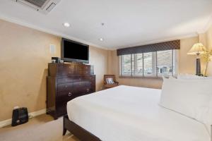 a bedroom with a white bed and a television at Lodge Tower 690 in Vail