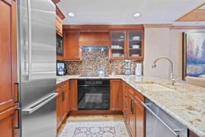 a kitchen with wooden cabinets and a stainless steel refrigerator at Lodge Tower 694 Two Bedroom Residence in Vail