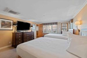 a bedroom with two beds and a flat screen tv at Lodge Tower 694 Two Bedroom Residence in Vail +15 photos