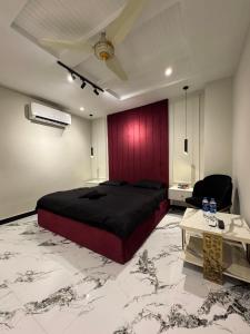 Un dormitorio con una cama grande y una pared roja. en Cozy One-Bed Studio Retreat, en Rawalpindi