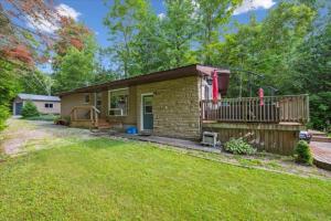 a small brick house with a balcony and a yard at Bay & Birch Getaway - Lakefront Living in Wiarton