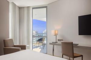 a hotel room with a bed and a desk and a television at AC Hotel By Marriott Santa Marta in Santa Marta