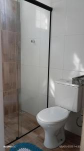 a bathroom with a toilet and a glass shower at Chalé Rota dos Guarás in Santo Amaro