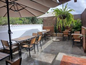 a patio with tables and chairs and an umbrella at Hotel El Descanso Cultural in Antigua Guatemala