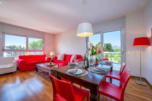 a living room with a table and red chairs at La Maison du Bonheur - Happy Rentals in Aldesago