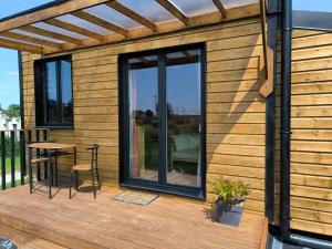 eine Holzhütte mit Tisch und Stühlen auf einer Terrasse in der Unterkunft La Mini Éole - Séjour insolite entre Rouen et Dieppe in Fresnay-le-Long