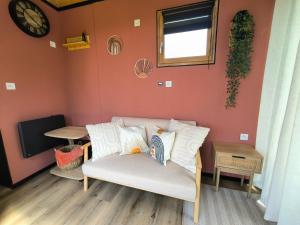 ein Wohnzimmer mit einer Couch und Kissen darauf in der Unterkunft La Mini Éole - Séjour insolite entre Rouen et Dieppe in Fresnay-le-Long