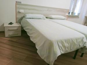 a large bed with white sheets and a night stand at Il Glicine B&b in Voltaggio