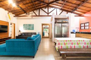 a living room with blue couches and a kitchen at Casa Tubarão - Piscina Aquecida em Camburi in Camburi