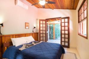 a bedroom with a blue bed and an open door at Casa Tubarão - Piscina Aquecida em Camburi in Camburi +71 photos