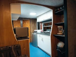a small kitchen with white cabinets and a television at Au Beau Rivage in Trois-Ponts