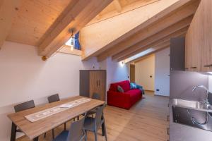 eine Küche und ein Esszimmer mit einem Holztisch und einem roten Sofa in der Unterkunft Alpinia in Moena