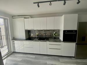 a kitchen with white cabinets and a black refrigerator at Claudiu apartament 's59 in Cluj-Napoca