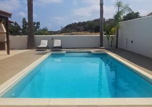 a swimming pool with two chairs next to a house at Eros Villa-Private Luxury Estate in Pissouri
