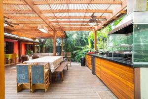 an outdoor dining area with a table and a kitchen at Casa Tubarão - Piscina Aquecida em Camburi in Camburi