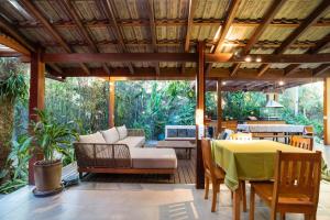 an outdoor patio with a table and a couch and chairs at Casa Tubarão - Piscina Aquecida em Camburi in Camburi