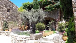 a stone building with a tree in a garden at Le Mouleyras in Saint-Montan