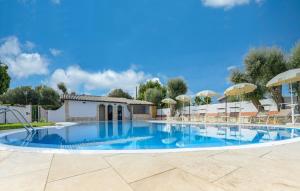 a large swimming pool with chairs and umbrellas at Villa Parisi in Floridia