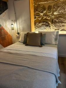 a bed with white sheets and pillows in a room at Mirada Do Roxo in Oia