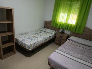 a bedroom with two beds and a window with green curtains at Paraiso alquiler vacacional in Málaga +63 photos