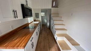 a kitchen with white cabinets and wooden floors and a staircase at Rate Drop! Enjoy the Simplicity-Teton Tiny House L in Tetonia