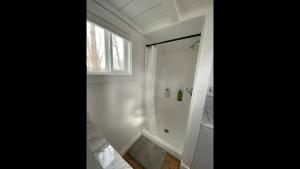 a white bathroom with a shower and a window at Rate Drop! Enjoy the Simplicity-Teton Tiny House L in Tetonia +12 photos