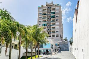 a tall building with palm trees in front of it at Apto lindo e confortável em frente à UFSC RVR0506 in Florianópolis