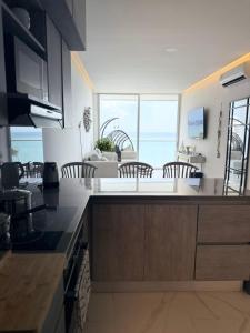 eine Küche mit einer Theke mit Stühlen und Meerblick in der Unterkunft Apto de Ensueño Frente al Mar in Playa Bello Horizonte