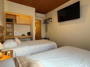 two beds in a room with a tv on the wall at Casa Agaves Conjunto Habitacional in Oaxaca City