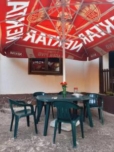 a table and chairs under a red umbrella at Vikendica Katarina in Ovčar Banja