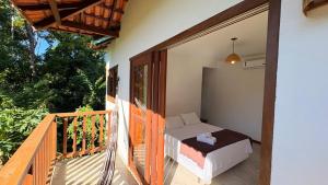 a porch with a bed on a balcony at Pousada Aroeira in Itaúnas