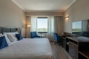 a hotel room with a bed and a desk and a television at Marriott Hotel Buenos Aires Ezeiza Airport in Ezeiza