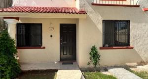 a house with a black door and two windows at Casa Amelia Victoria in Mérida