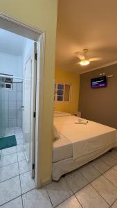 a bedroom with a large bed and a tv on the wall at Grand Maré Hotel in Peruíbe
