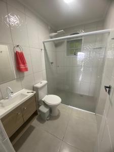 a bathroom with a shower and a toilet and a sink at Suites mirante da Enseada in Guarujá +7 photos