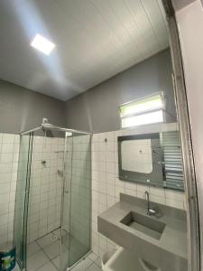 a bathroom with a shower and a sink and a mirror at Chalé 01 Acqua Park - 06 km de Presidente Figueiredo-AM in Presidente Figueiredo