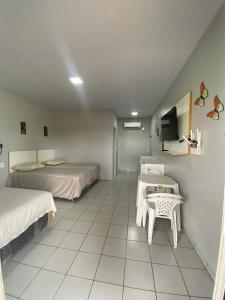 a room with two beds and a table in it at Chalé 01 Acqua Park - 06 km de Presidente Figueiredo-AM in Presidente Figueiredo