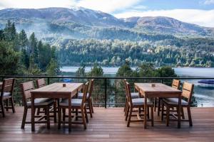 a wooden table and chairs on a deck with a view at Auria Angostura in Villa La Angostura